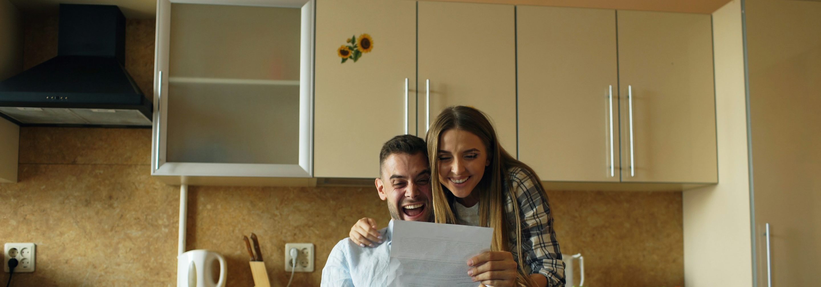 A couple in their kitchen, relieved as they read a letter together