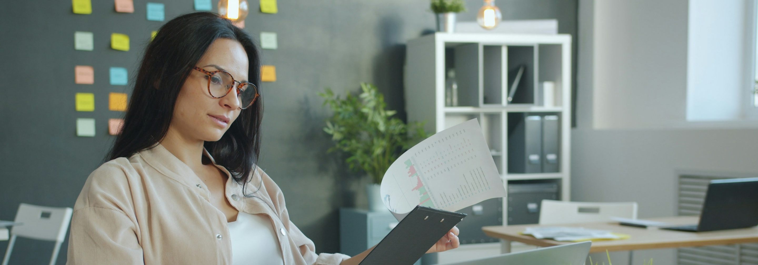 A woman carefully re-reading a document at her desk