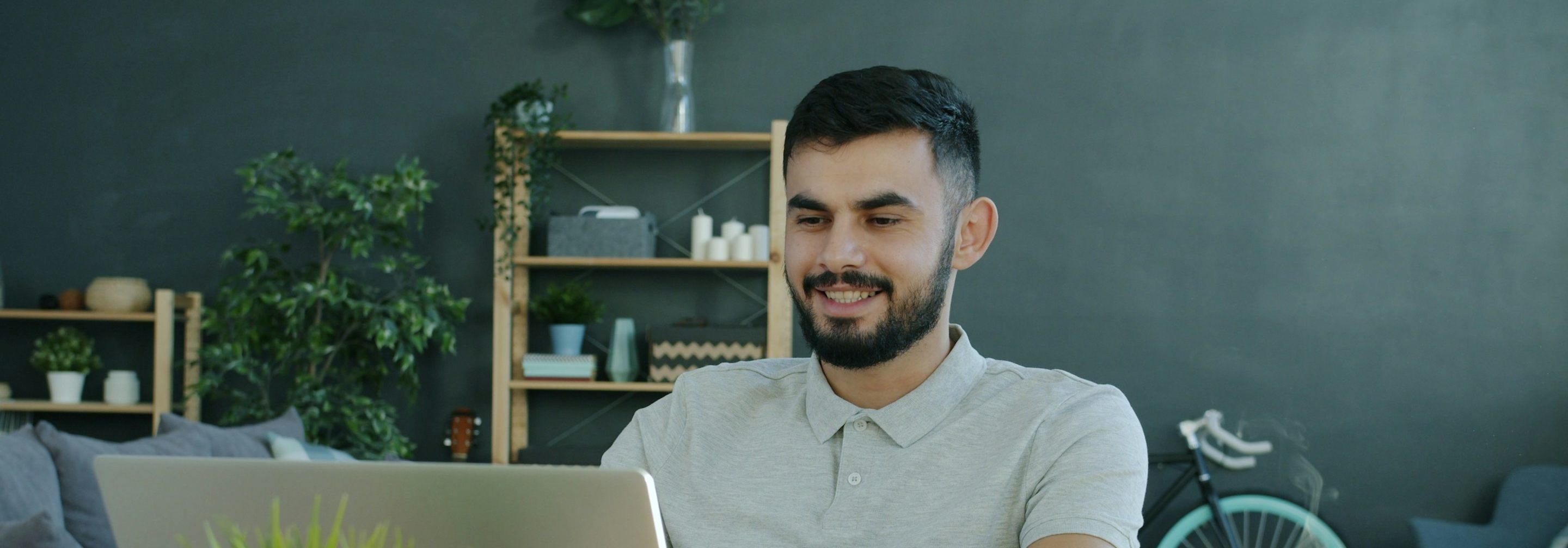 A man smiling as he works on his laptop at home