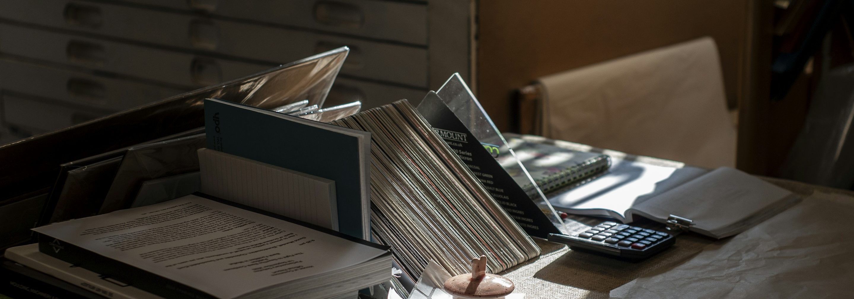 A desk piled with old documents, folders, and a calculator